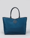 A stacked leather logo plaque details this timeless Tory Burch tote bag, offering a distinctive counterpart to its cool, casual construction.