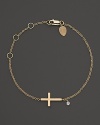 A modern cross bracelet in yellow gold with diamond accent.