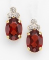 These simply elegant earrings feature three sparkling diamonds resting atop a rich garnet stone. Set in 14K gold. For pierced ears only.