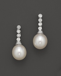 Diamonds add sparkle to shimmering pearl studs set in gold. Diamonds add sparkle to shimmering pearl studs set in gold.