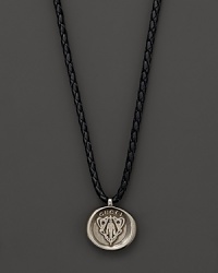 Silver Gucci charm on a braided black natural leather necklace.