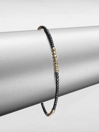 A simple chic piece that features faceted beads in blackened sterling silver accented with four, 14k gold beaded sections. Blackened sterling silver14k goldDiameter, about 2.5Slip-on styleMade in USA