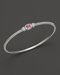 Two hearts flank a cushion-cut pink corumdum on this slim bangle. Two hearts flank a cushion-cut pink corumdum on this slim bangle.