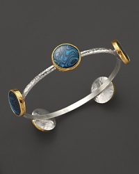 A bold sterling silver bangle from Gurhan with Paua shell stations in 24K yellow gold. A bold sterling silver bangle from Gurhan with Paua shell stations in 24K yellow gold.