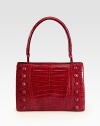 A glossy crocodile design with self covered stud accents.Adjustable top handle, 7½-8 dropHinged magnetic closureProtective crocodile covered feetOne inside zip pocketTwo inside open pocketsSuede lining11W X 7½H X 3DImported