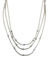 Add just the right amount of layers to amp up your look. AK Anne Klein necklace features three rows of woven chains accented by donut-shaped beads. Crafted in silver tone mixed metal. Approximate length: 16 inches.